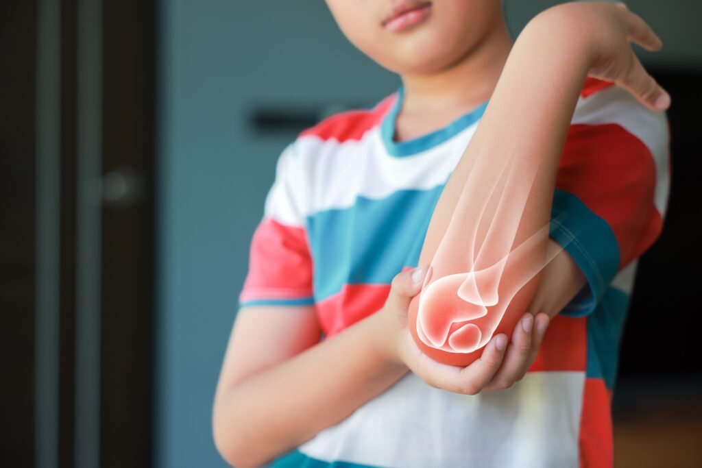 A young child crying and holding their injured elbow close to their body after a sudden pull or fall.